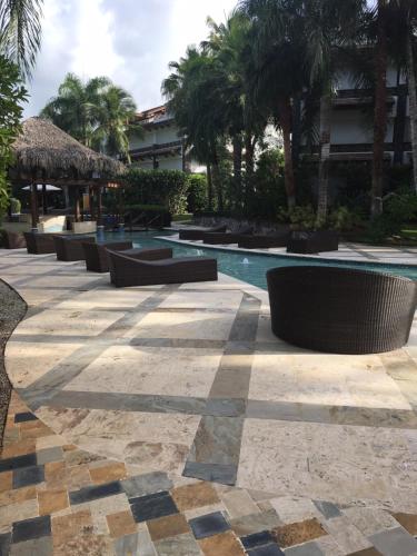 a pool at a resort with benches and palm trees at Apartment Balcones Del Atlantico in Las Terrenas