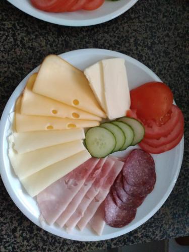 a plate of different types of cheese and vegetables at Penzion Pomodoro in Vrbno pod Pradědem