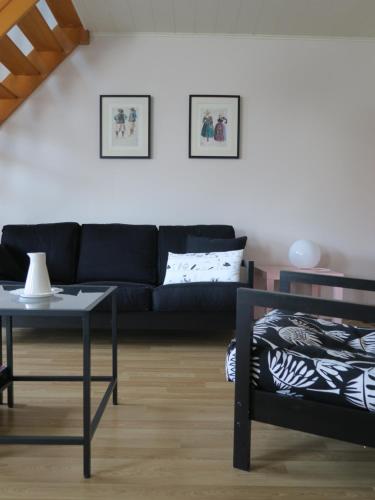 ein Wohnzimmer mit einer schwarzen Couch und einem Tisch in der Unterkunft Kerhervé in Cléden-Poher