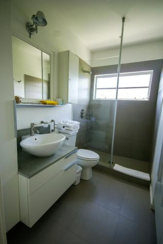 a bathroom with a sink and a toilet and a shower at Antigua Village Beach Resort in Saint Johnʼs