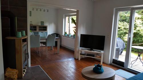 ein Wohnzimmer mit einem TV und einem Tisch mit Stühlen in der Unterkunft Ferienhaus Martha in Fehmarn