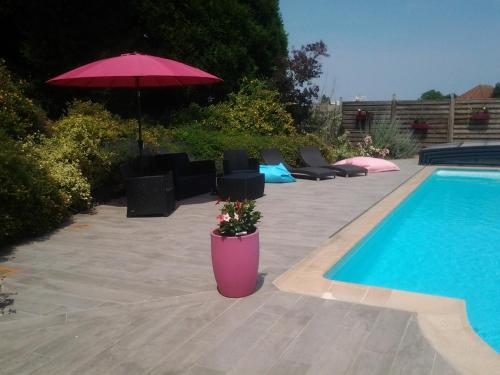 a pool with a pink planter with a pink umbrella at Château du Clos Mortier in Saint-Dizier