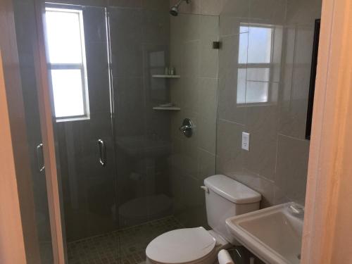 a bathroom with a shower and a toilet and a sink at Pelican By The Sea in Pompano Beach