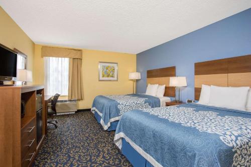 a hotel room with two beds and a flat screen tv at Days Inn by Wyndham Raleigh-Airport-Research Triangle Park in Morrisville