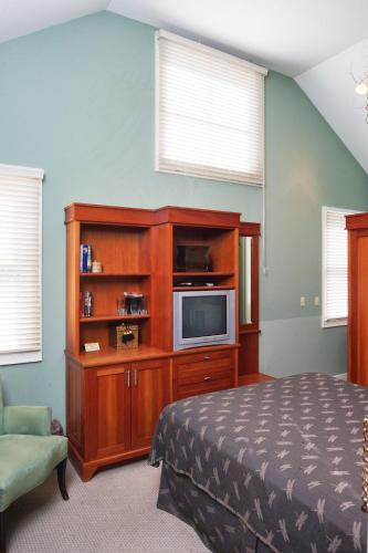 a bedroom with a bed and a cabinet with a television at Hotel Mac in Richmond