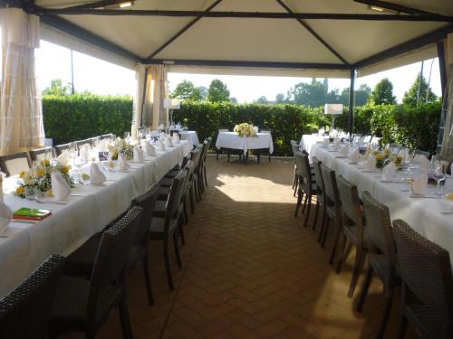 una mesa larga con mesas blancas y sillas en una carpa en Hotel La Fornace, en San Vicenzo di Galliera