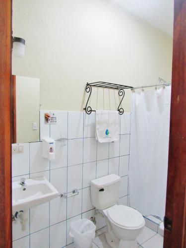 a white bathroom with a toilet and a sink at Hotel Palmeras de Elim in Caño de la Laja