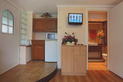 a kitchen with wooden cabinets and a tv on the wall at Pokoje Gościnne Gazda in Polanica-Zdrój