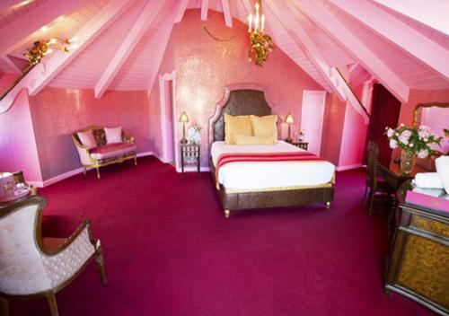 a pink bedroom with a bed and a chair at Madonna Inn in San Luis Obispo