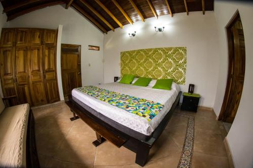a bedroom with a large bed with green pillows at Hotel La Coqueta in Montenegro