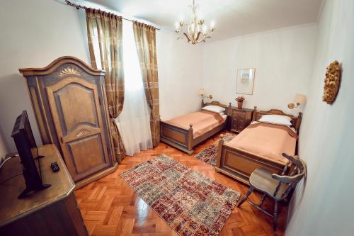 シビウにあるAntique Apartment Sibiuのベッドルーム1室(ベッド2台、テレビ、テーブル付)