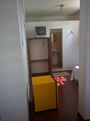 a room with a yellow table and a tv on the wall at Hotel Minas in Itamaraju