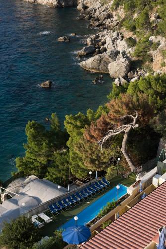 a swimming pool with blue umbrellas next to the water at Hotel Weber Ambassador in Capri