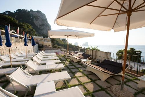a group of lounge chairs and umbrellas on a beach at Hotel Weber Ambassador in Capri