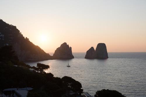 a sunset over the ocean with rocks in the water at Hotel Weber Ambassador in Capri