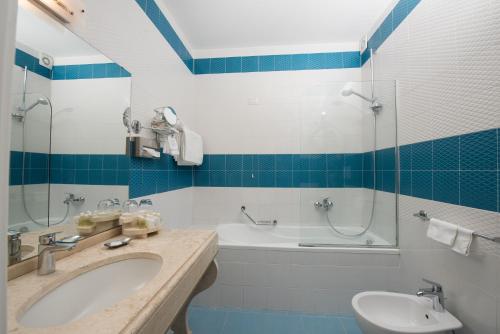 a bathroom with a sink and a tub and a toilet at Hotel Weber Ambassador in Capri
