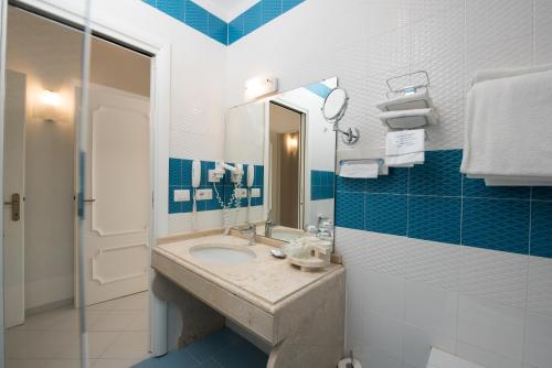 a blue and white bathroom with a sink and a mirror at Hotel Weber Ambassador in Capri