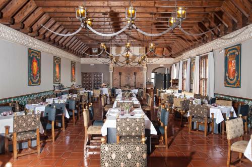 a dining room with tables and chairs and a chandelier at Parador de Alcañiz in Alcañiz