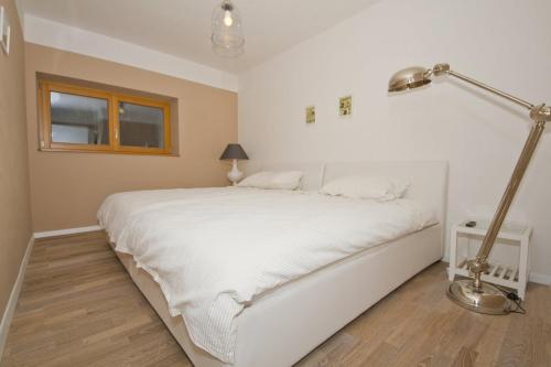 a white bed in a bedroom with a lamp at Apartments Mengore in Tolmin