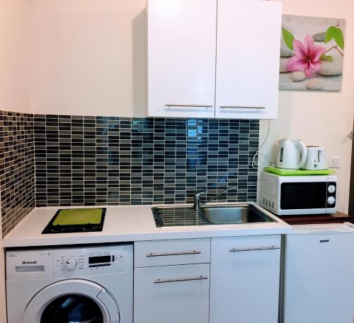 a white kitchen with a sink and a microwave at Appartement Mimosa, tram 2, parking in Montpellier