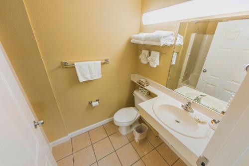 ein Badezimmer mit einem Waschbecken, einem WC und einem Spiegel in der Unterkunft The Islander Inn in Ocean Isle Beach