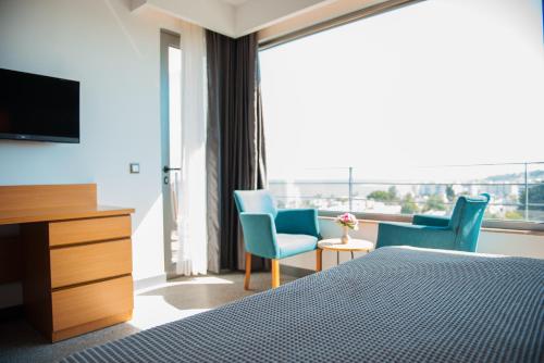 een slaapkamer met een bed en 2 stoelen en een televisie bij Port Marina Hotel in Karatas