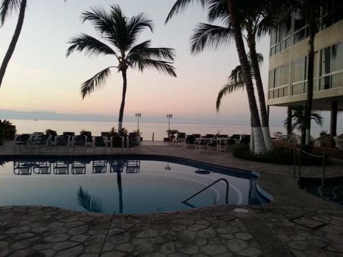 a pool at the beach with palm trees and a hotel at Suites Atlas - Ocean Front in Bucerías