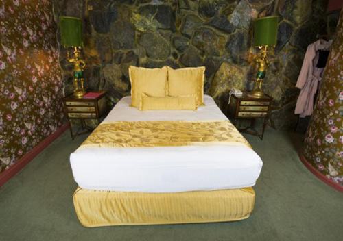 a bedroom with a large bed in a stone wall at Madonna Inn in San Luis Obispo