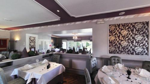 ein Esszimmer mit Tischen und Stühlen sowie ein Restaurant in der Unterkunft Logis Hôtel-Restaurant La Croix Couverte in Mayenne