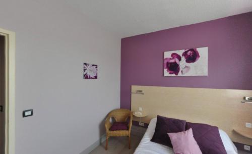 a bedroom with a bed with a purple wall at Logis Hôtel-Restaurant La Croix Couverte in Mayenne