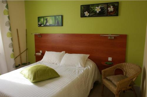 a bedroom with a white bed with a wooden headboard at Logis Hôtel-Restaurant La Croix Couverte in Mayenne