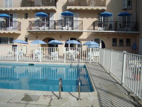 a swimming pool in front of a building with umbrellas at Hôtel de la Poste Piscine in Peymeinade