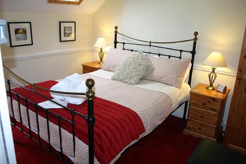 a bedroom with a bed with a red blanket and two lamps at Brixham House in Brixham