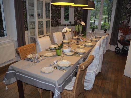 une grande table avec des nappes et des assiettes blanches dans l'établissement Chateau du Pont Jean, à Fresse-sur-Moselle