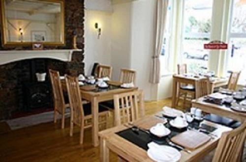 a dining room with tables and chairs and a fireplace at Brixham House in Brixham