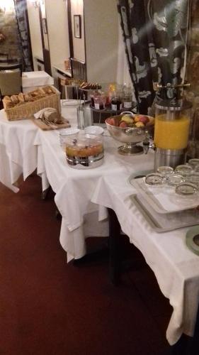 a table with white clothed tables with food and drinks at Hôtel de La Croix d'Or in Avranches
