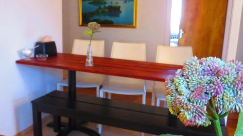 a wooden table with a vase of flowers and chairs at Guesthouse Kálfafellsstadur in Kálfafellsstaður