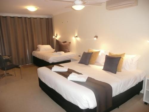 
a hotel room with two beds and two lamps at Getaway Inn Boutique Guest house in Nulkaba
