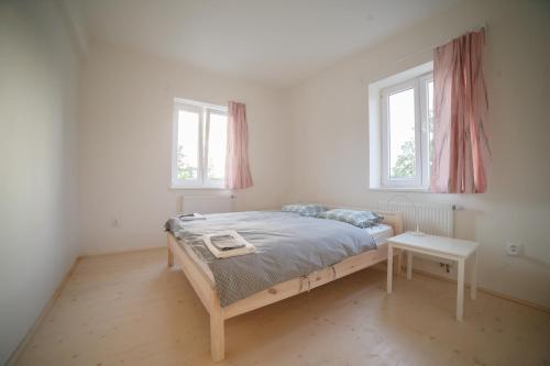a white bedroom with a bed and two windows at Ubytování NAPOLI in Stará Červená Voda