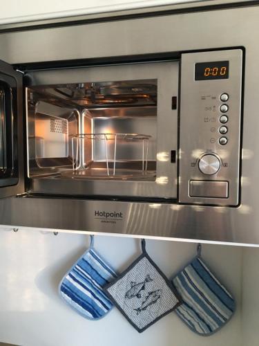 a microwave oven with two mitts in a kitchen at Vivenda da bela vista in Costa da Caparica