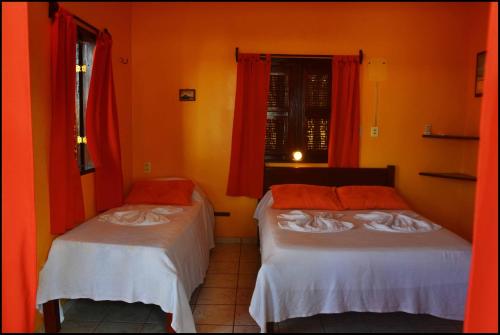two beds in a room with orange walls at Pousada Sahara in Jericoacoara