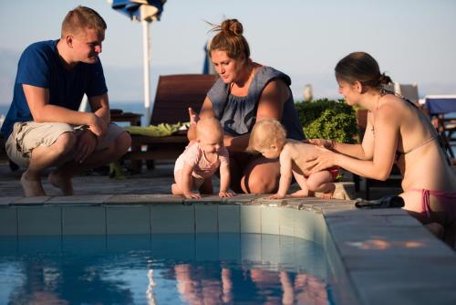 a group of people sitting around a swimming pool with babies at Spacious apartment on the beachfront in Melission