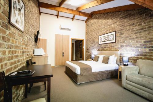 a bedroom with a bed and a brick wall at The Lodge in Hahndorf