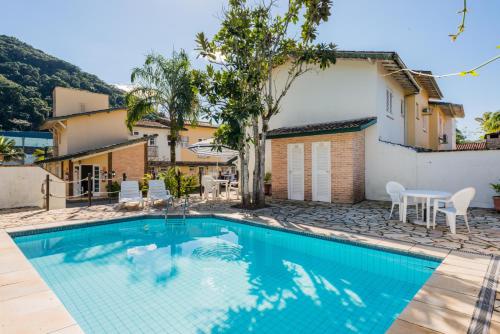 a swimming pool with a table and chairs next to a house at Bhaus Juqueí | Beach House | Praia in Juquei