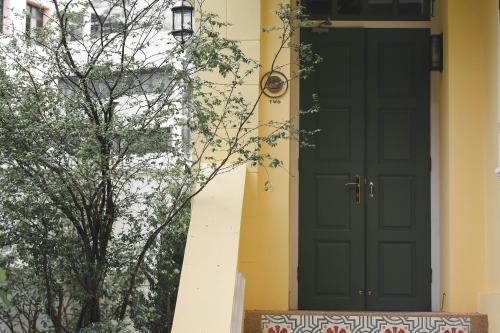 a green door on a yellow house with a tree at Baan 2459 Heritage House in Bangkok