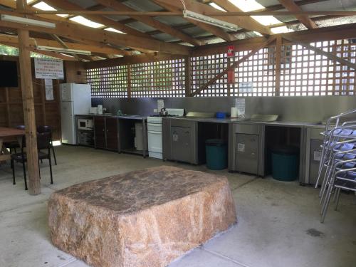 a large stone table in a kitchen with tables and chairs at A'Wangralea Caravan Park in Mallacoota