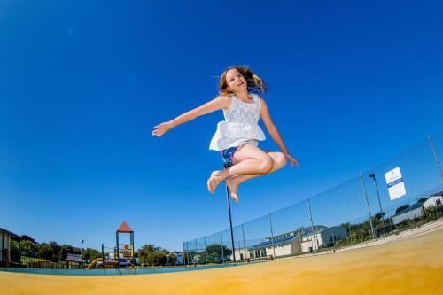 a young girl jumping in the air near a fence at NRMA Warrnambool Riverside Holiday Park in Warrnambool