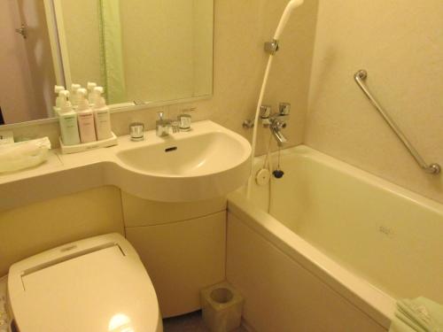 uma casa de banho com um lavatório, um WC e uma banheira em Yamagata Eki Nishiguchi Washington Hotel em Yamagata