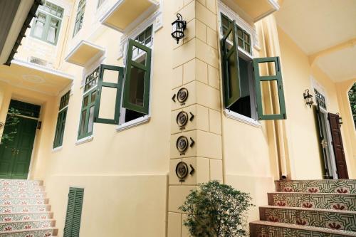 a facade of a house with windows and stairs at Baan 2459 Heritage House in Bangkok