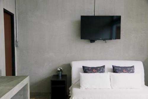 a tv on a wall above a bed with pillows at Mighty Mountain Thailand in Kaeng Krachan